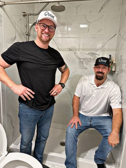 A couple of men standing next to each other in a bathroom