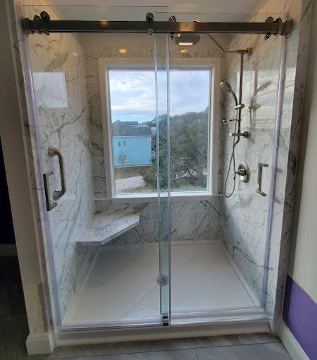 A bathroom with a walk in shower next to a window